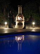 Buschbeck Rondo 3-in-1 Outdoor Fireplace at night with the pool