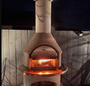 Buschbeck Rondo 3-in-1 Outdoor Fireplace at night with fire