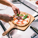 Person preparing pizza in Ooni 12" Bamboo Pizza Peel