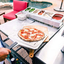 person using Ooni 14” Perforated Peel with pizza on top to be placed on board
